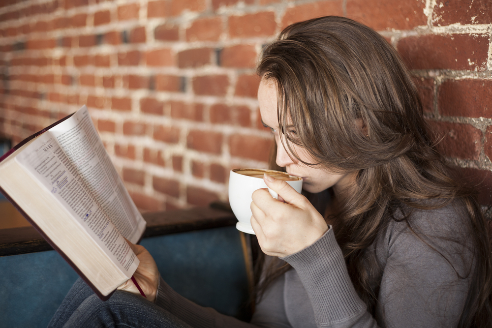 woman sips coffee and reads Bible