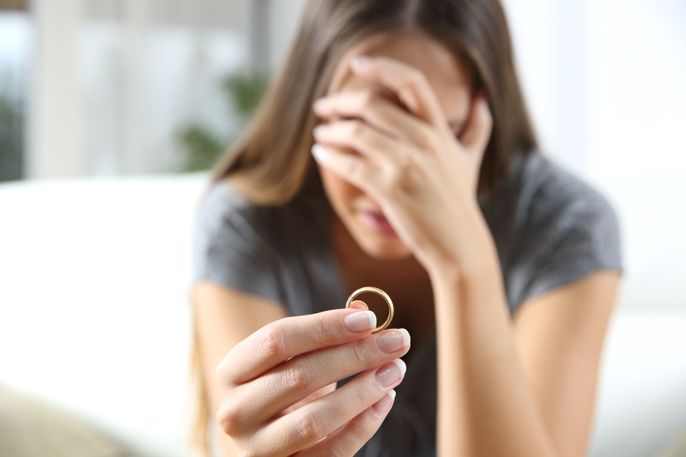 Woman is distressed and holding wedding ring
