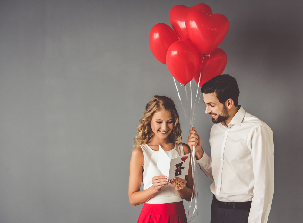 young man gives his girlfriend a card and balloons