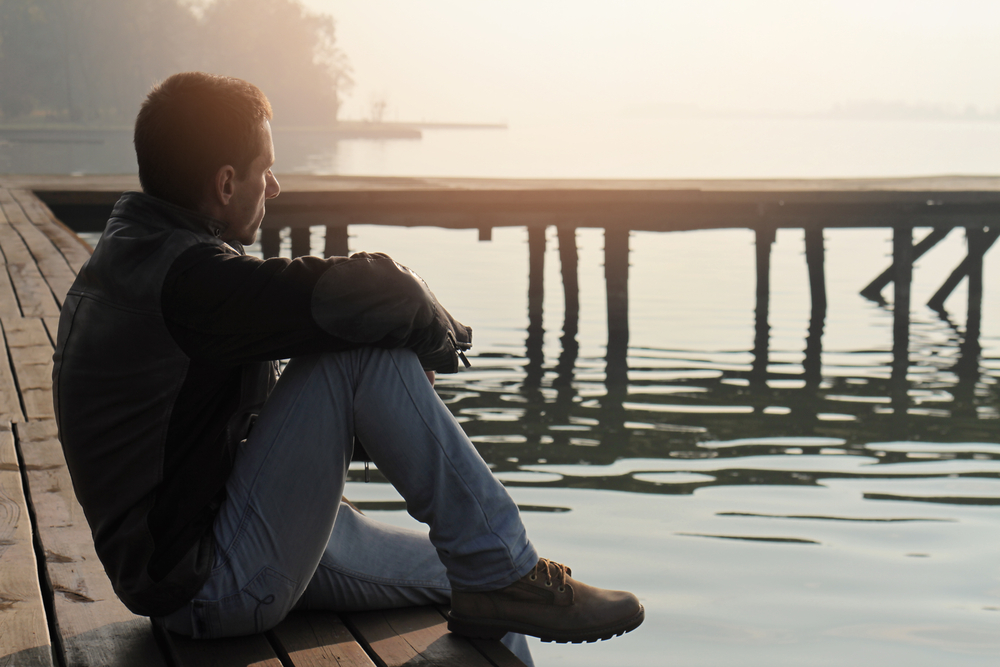 man sits alone on pier