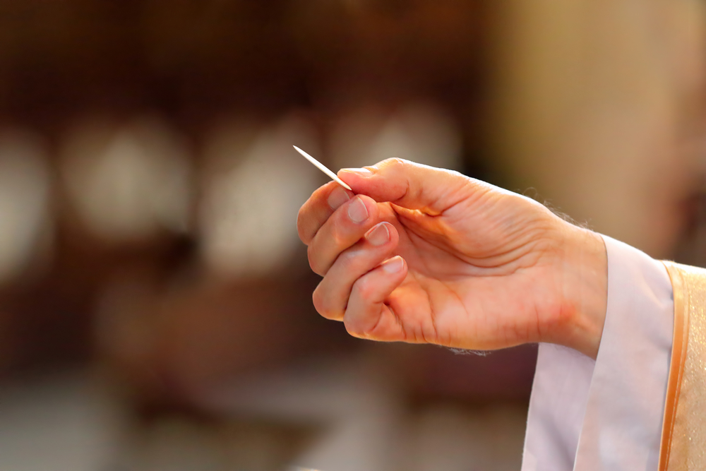 priest distributes Holy Communion