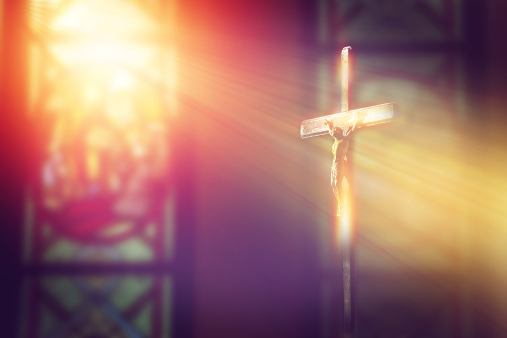Light streams through stained glass onto crucifix