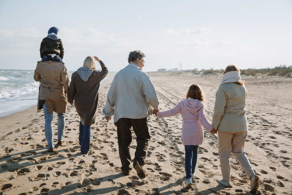 family with grandparents walks on beach