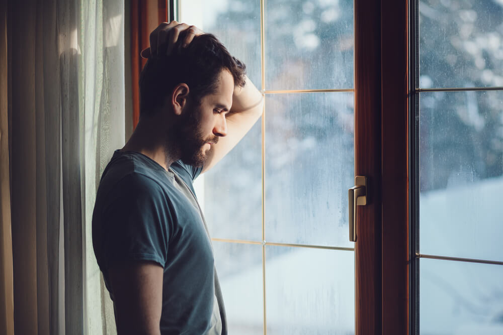young man looks out window