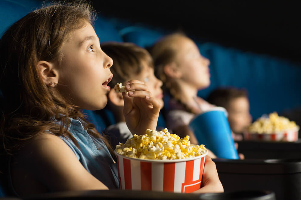 Kids eating popcorn at movie theatre