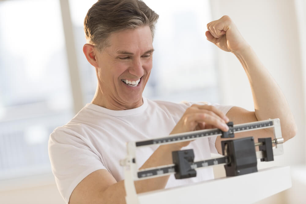man weighs himself at gym