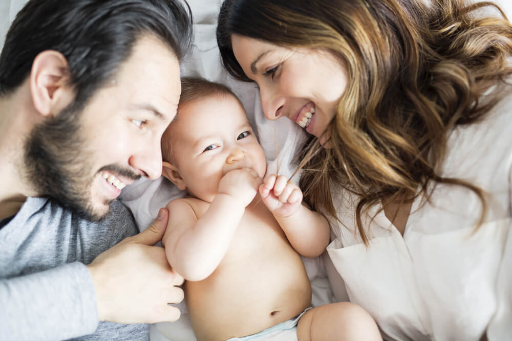 mom and dad smile lovingly at baby