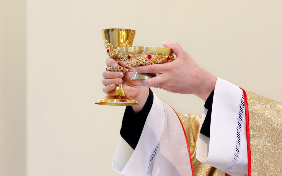 priest elevates Body and Blood of Christ