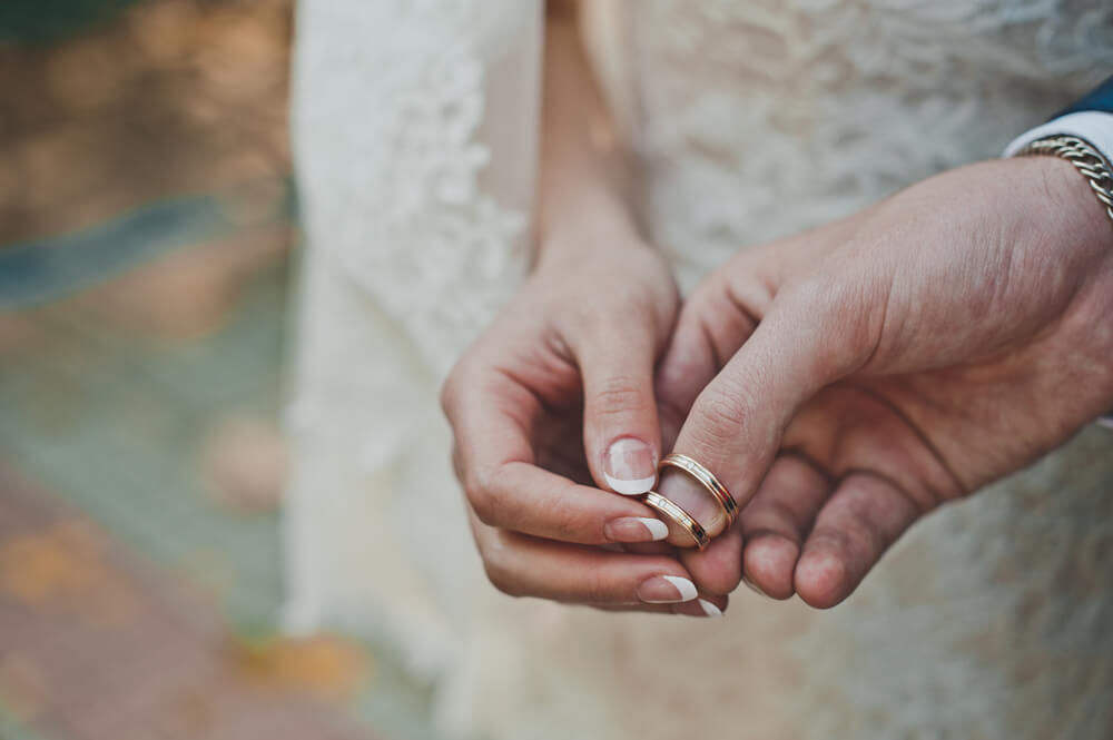couple holds wedding rings