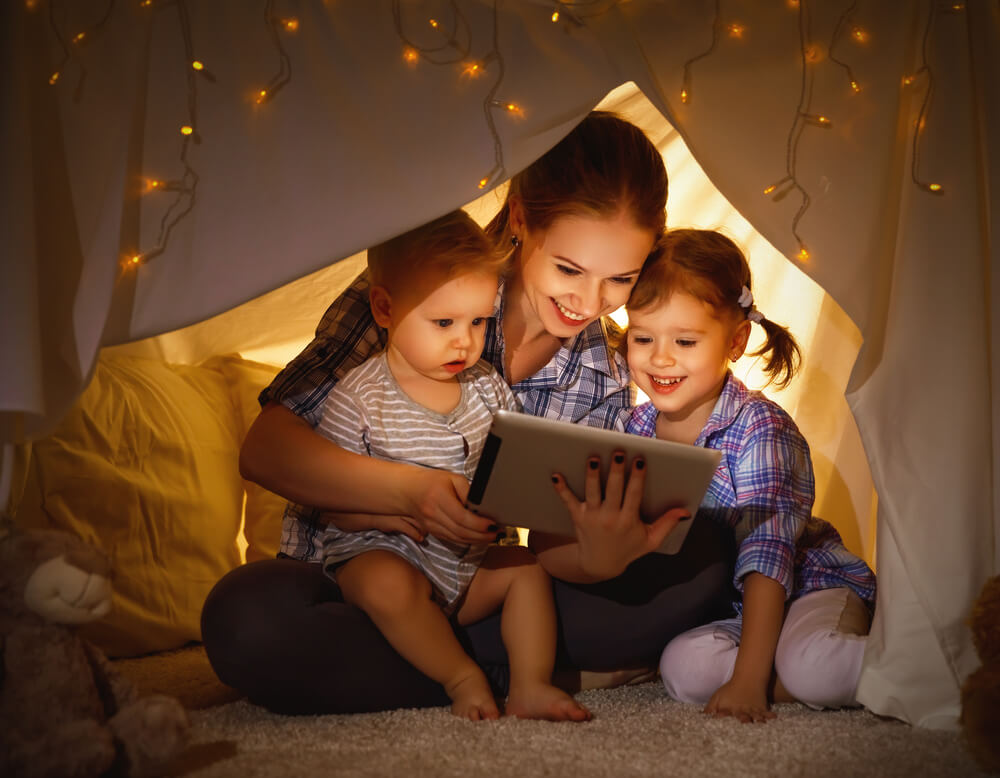 Mom and kids use tablet in tent