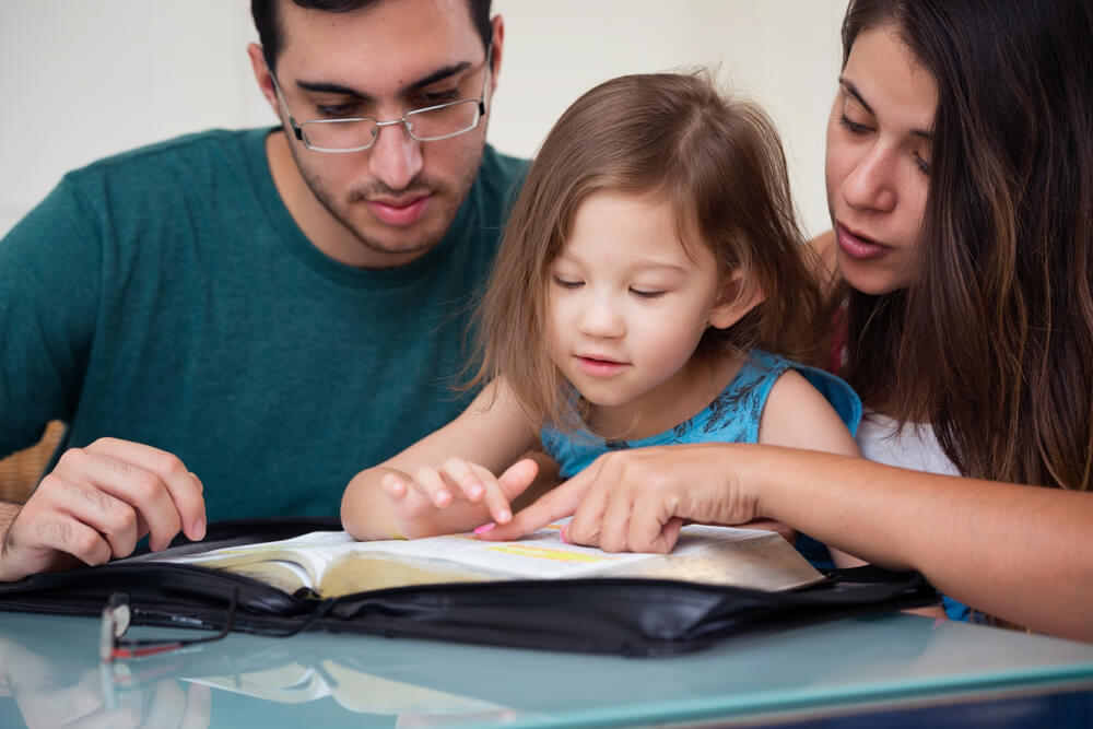 mom and dad read Bible with daughter