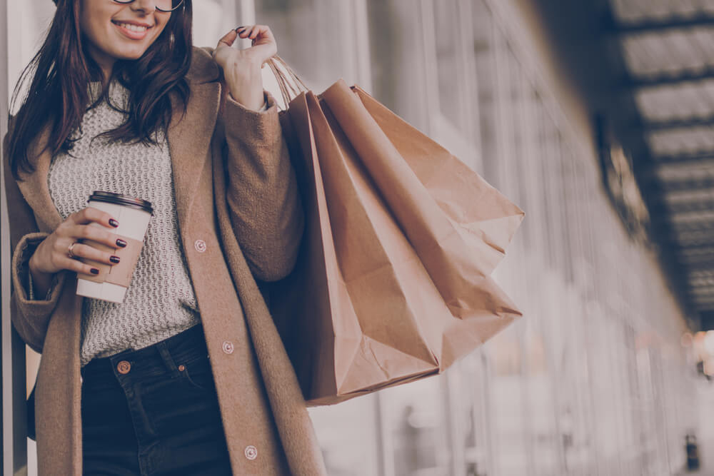 woman holding coffee and shopping bags