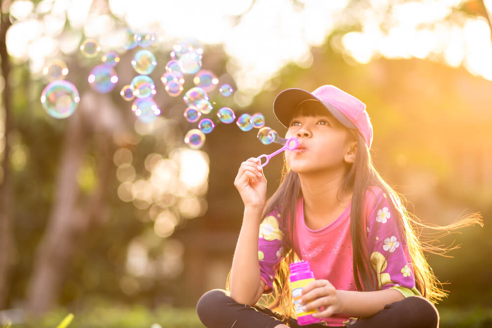 little girl blows bubbles