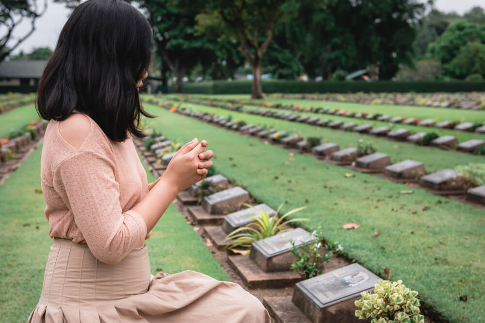 woman knees in prayer at cemetery