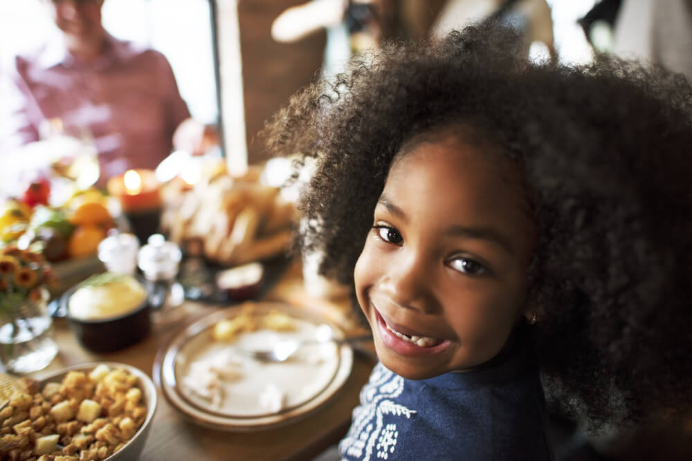 little girl smiles at Thanksgiving dinner