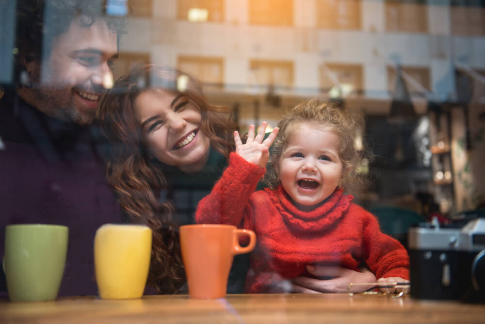 Young family smiles and waves out window