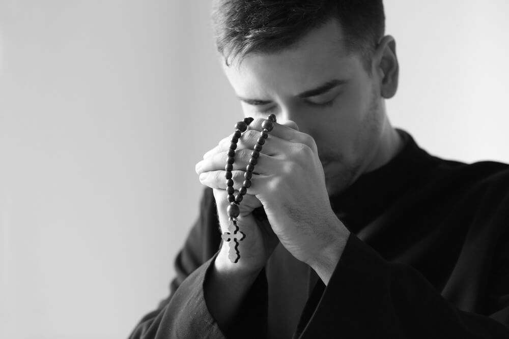 young priest prays Rosary