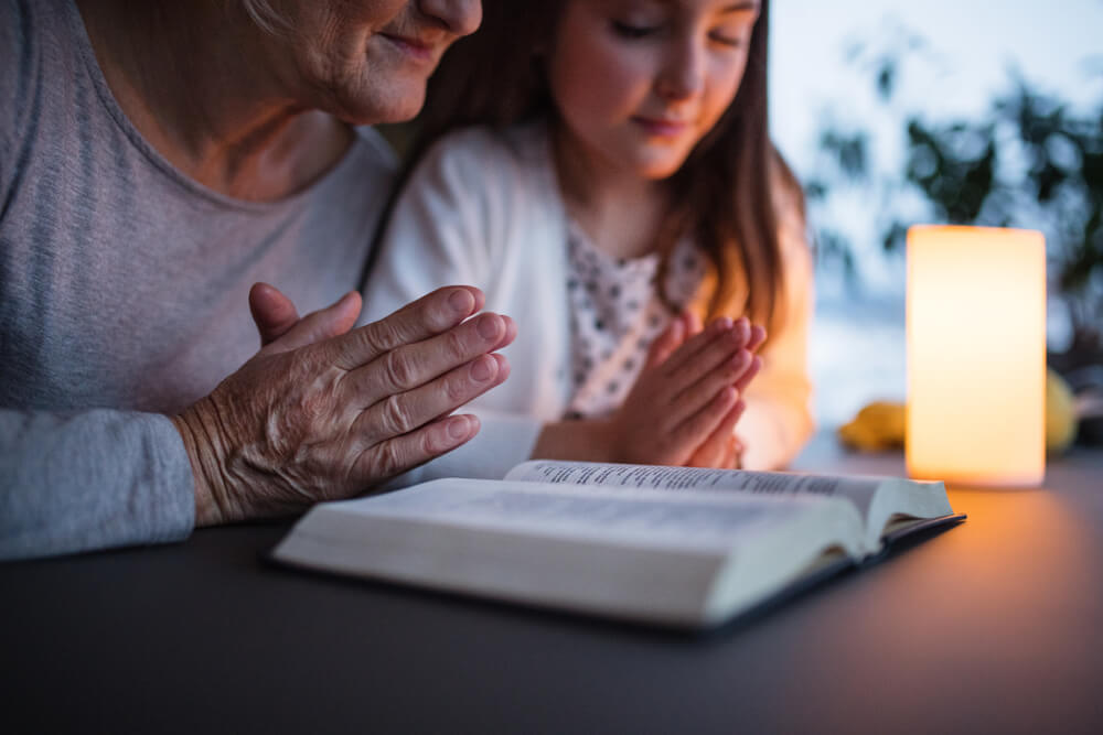 Grandma and granddaughter pray together at home