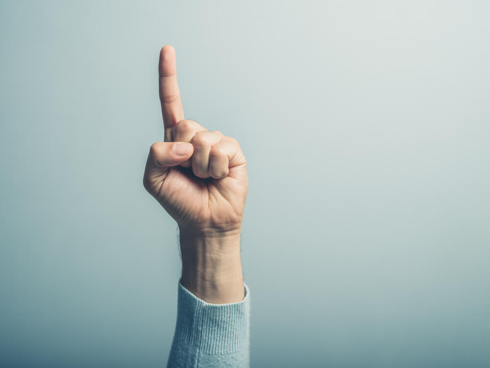 man raises pointer finger in the air to say, 'one'