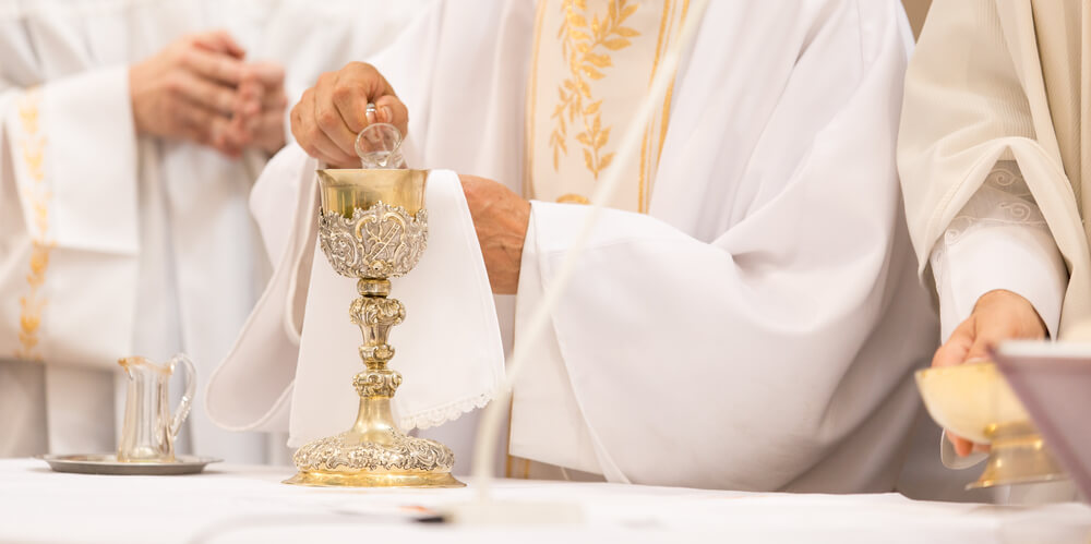 priest pours water into wine and says secret prayers