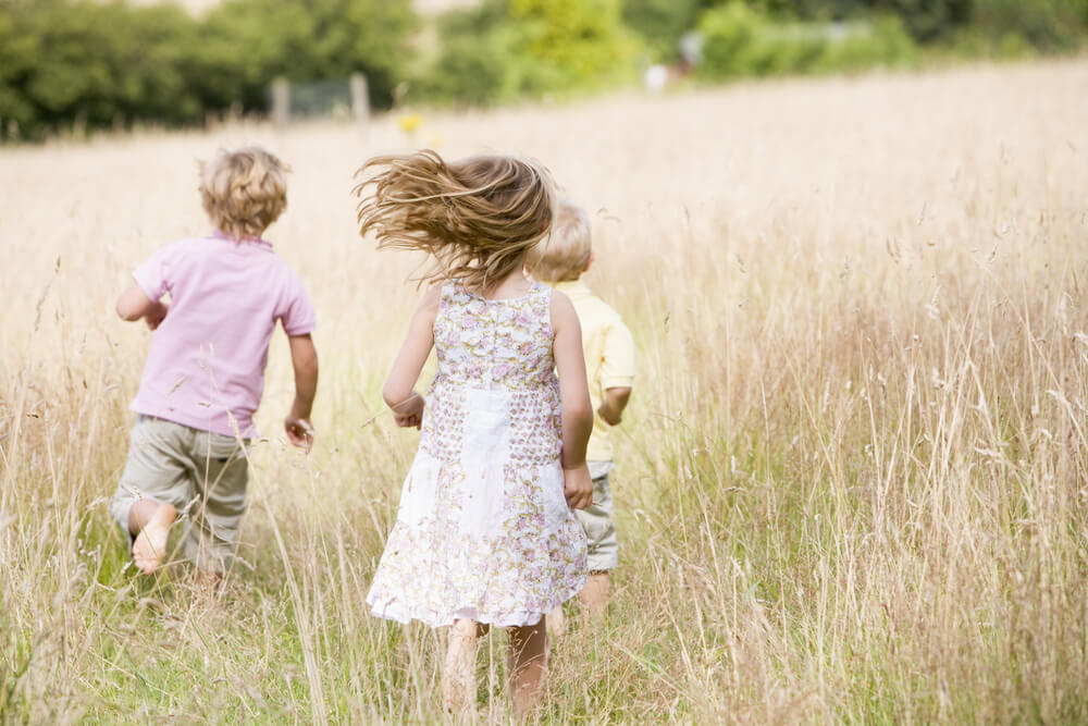 three children running through a field
