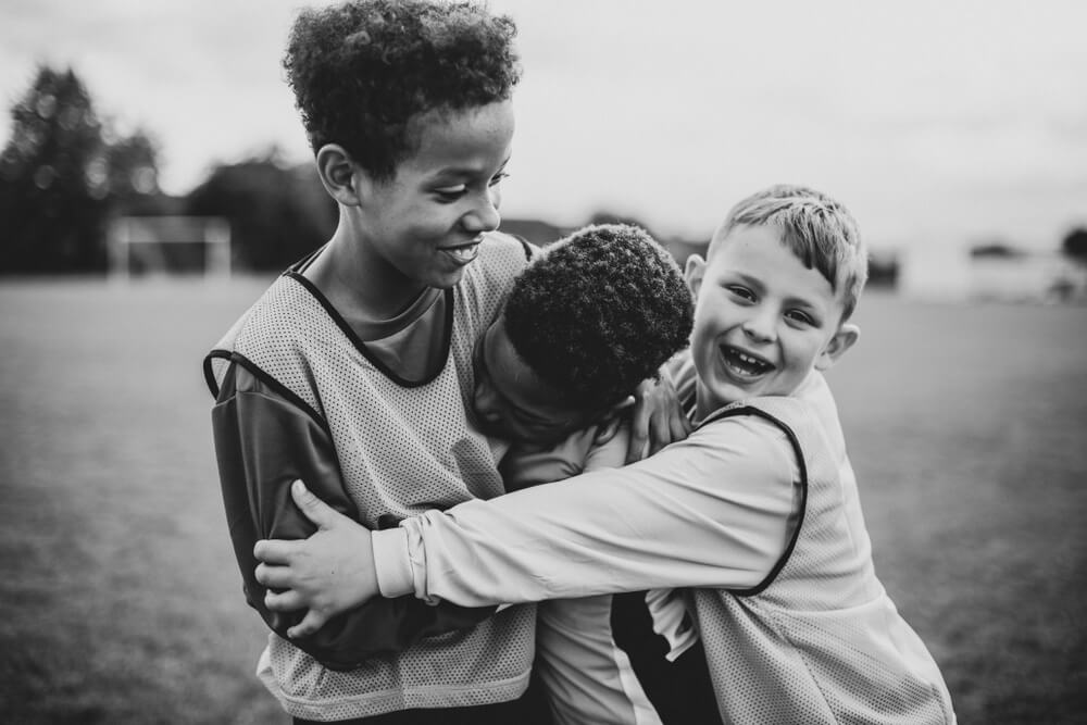 three boys hug at soccer practice