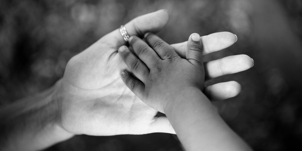 White mother holds black son's small hand
