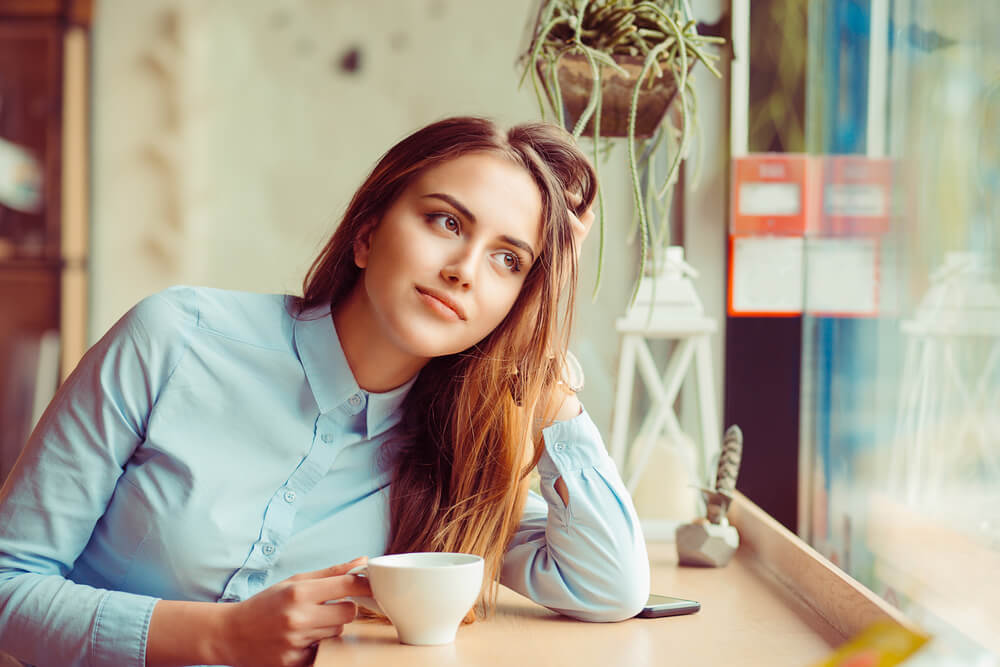 young woman sits quietly and peacefully with coffee
