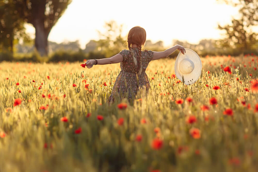 woman runs through field of flowers