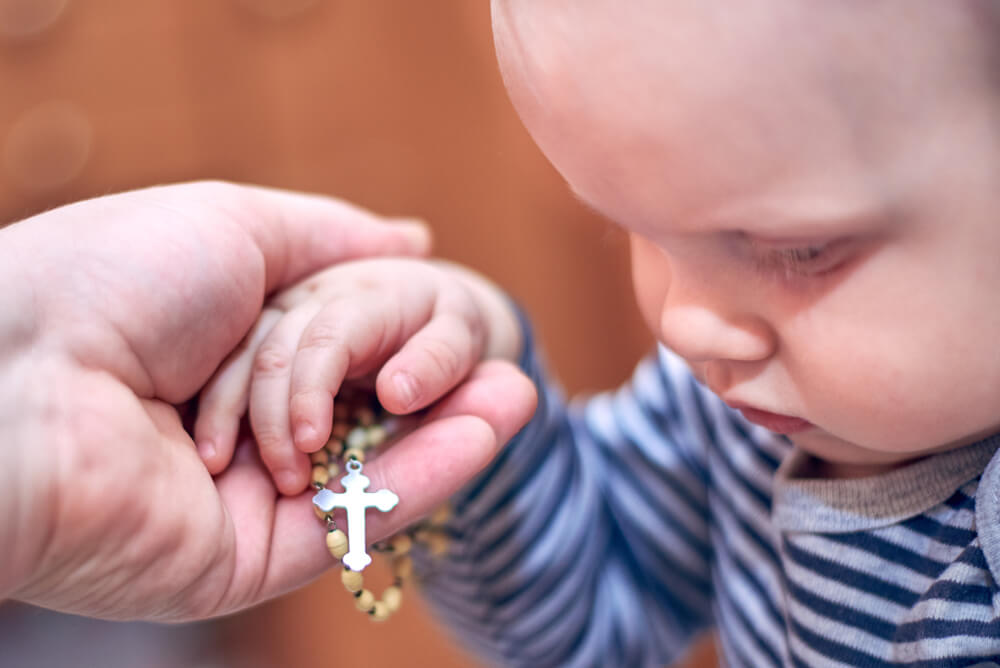 Baby hold Rosary beads