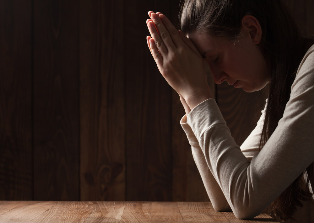 woman bows head in humility and prayer
