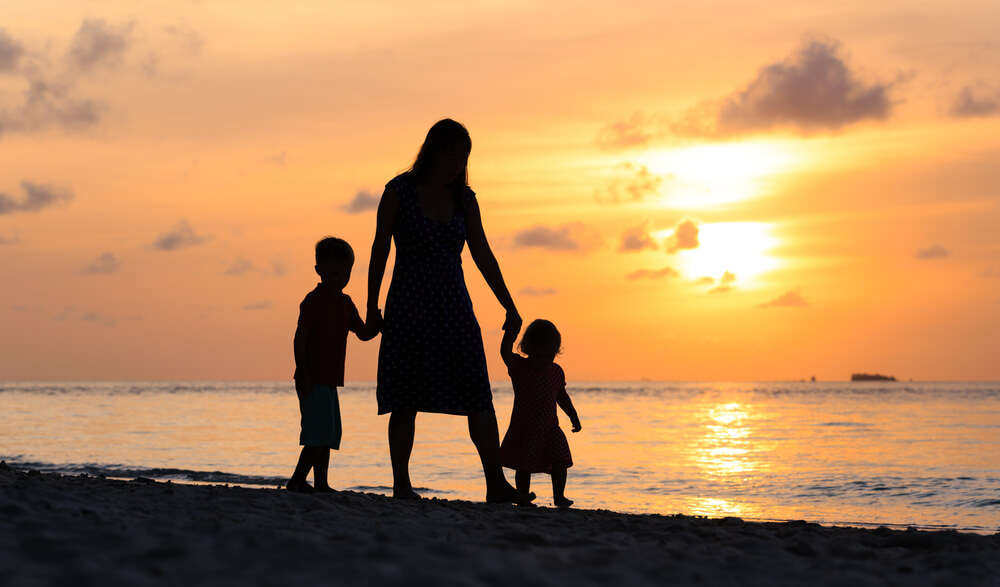 Mother and two children walk on beach
