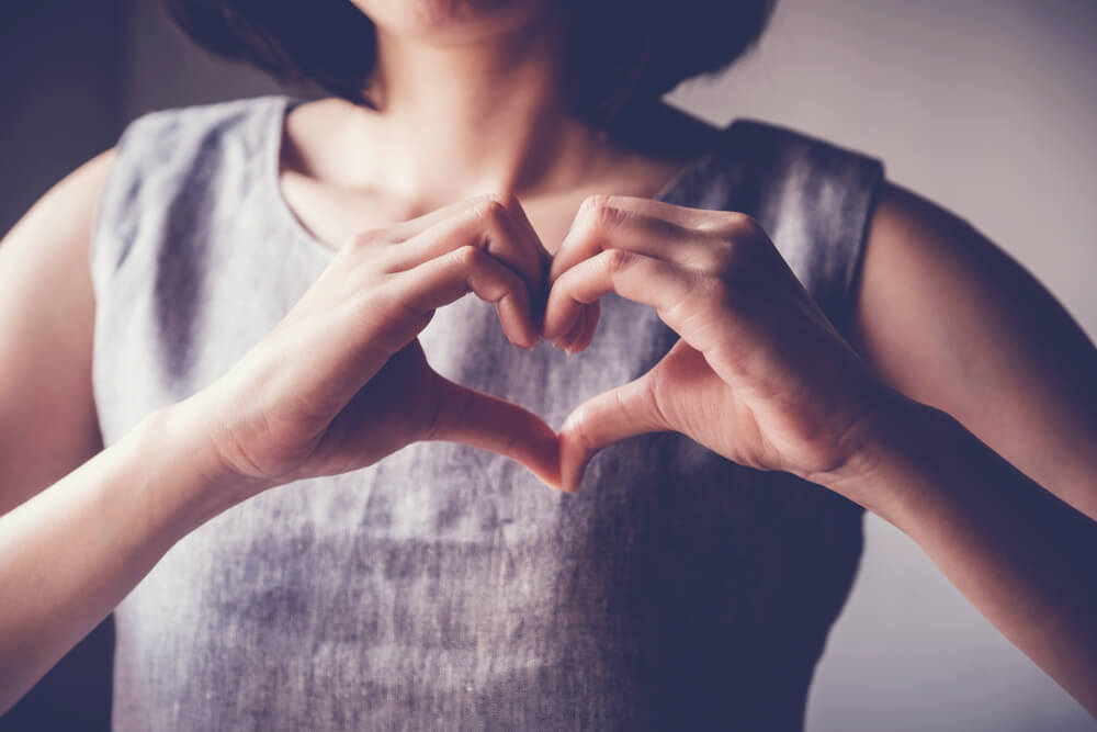 grateful woman makes heart with hands to show gratitude