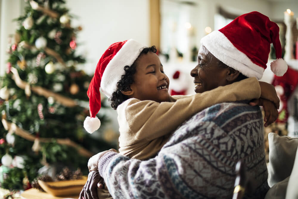 child and grandparent hug and smile at Christmas