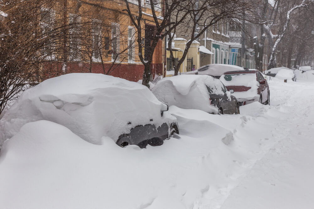 city street with cars in snowbank