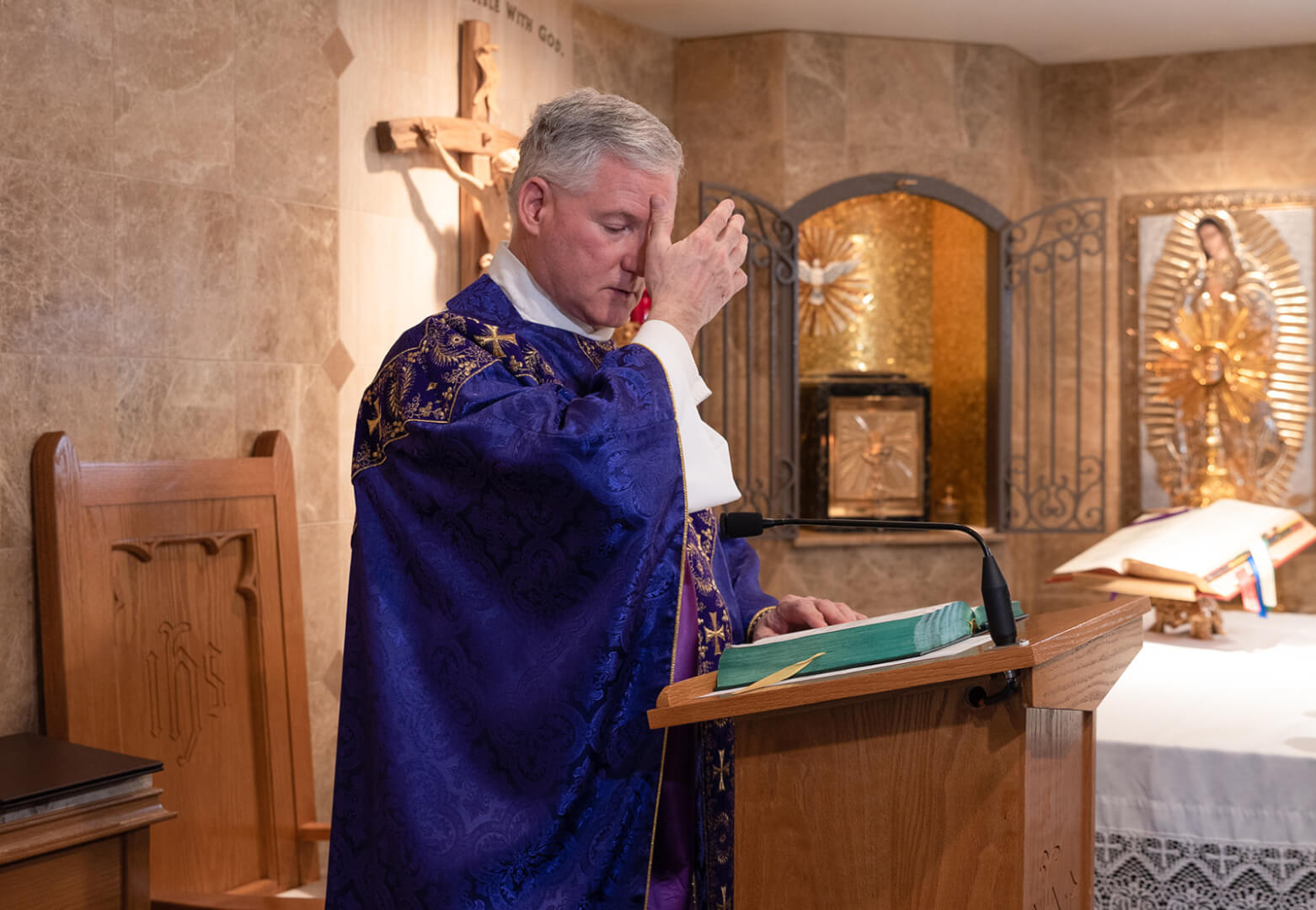 Priest blesses himself before proclaiming the Gospel