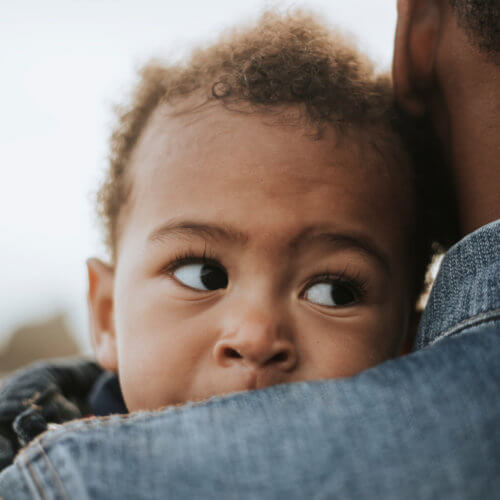 baby looks over dad's shoulder