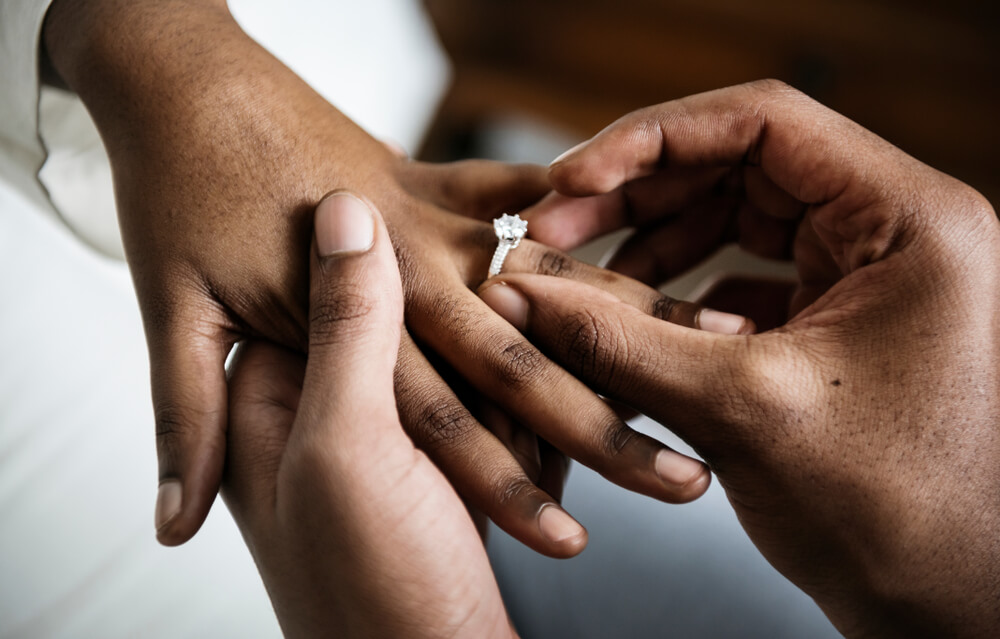 man puts engagement ring on woman's finger