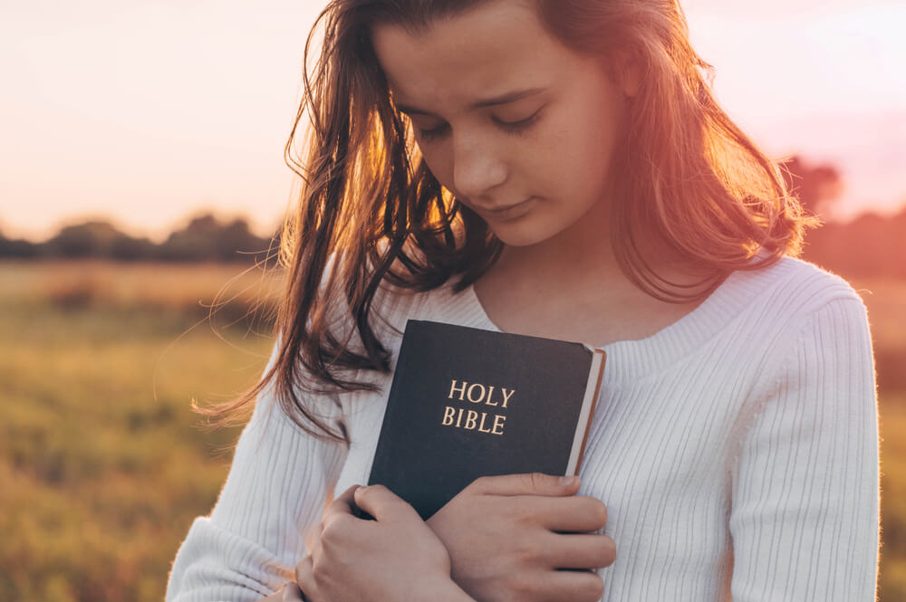 young woman hugs bible
